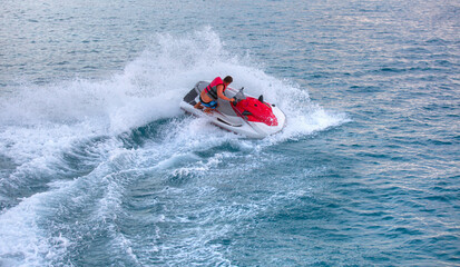 A man on jet ski jump on the wave - Man drives red and white jet ski on turquoise sea
