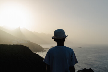 Back silhouette of a teenage girl wearing a hat at sunset at a viewpoint in Tenerife 