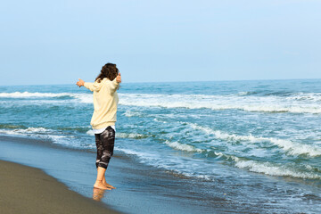 Young woman opening arms while walking on the white beach