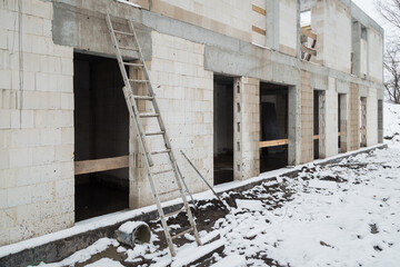 Home building in winter. House construction. A ladder in the foreground.