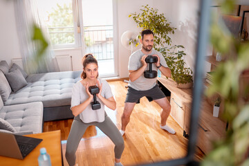 Couple doing squats using dumbbells