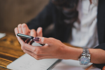 Close up of business woman is using smartphone for searching or watching social media to entertain while breaking time at workplace. Female manager is chat with her friend during break time.