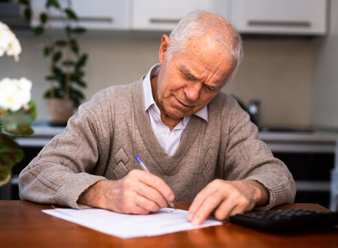 elderly senior writing letter on paper at home
