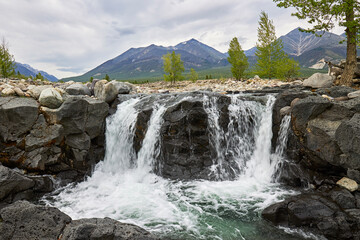 Naklejka na ściany i meble Waterfall on the river against the background of mountains