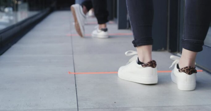 Social distance, shoes and people standing in a row outdoor of a medicare clinic for a covid test. Healthcare, safety and closeup of feet with sneakers in a line or queue outside a medical center.