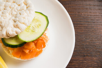 Flatlay, sandwich with salmon and cucumber and lemon on white plate