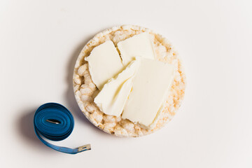 The concept of proper nutrition, diet and healthy lifestyle. Crispy rice bread with butter and measuring tape on a white background