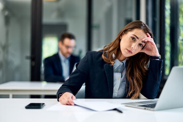 Portrait of a tired businesswoman sitting at the office and working on a laptop.