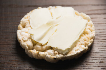 Delicious crispy aired rice bread with butter macro on wooden background with copy space. Diet and healthy eating concept.