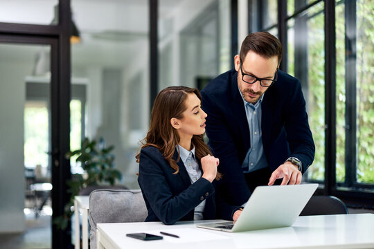 A male boss checks a new project done by a female employee at the office.