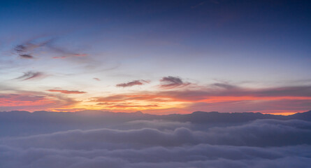 Fototapeta na wymiar sunset sky clouds over mountains with sea mist in the morning with colorful sunrise