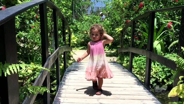 Little girl in pink summer dress walking in beautiful park with butterflies, discovering nature and wild life. High quality FullHD footage