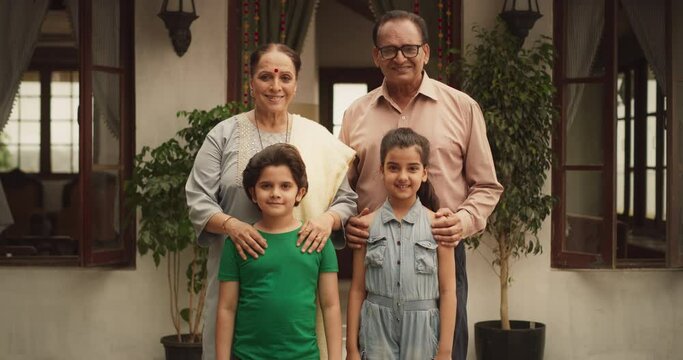 Portrait of Happy Indian Family Posing Together in Beautifully Authentic Mumbai House. Senior Grandparents and Their Two Cute Grandkids Looking at the Camera, Happily Taking a Family Photo. Zoom in