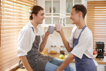 LGBT gay couple holding a cup of coffee and taking a break in the kitchen