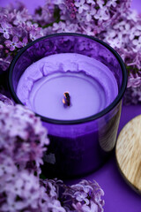 Obraz na płótnie Canvas Purple candle next to purple lilac. spa concept. purple background