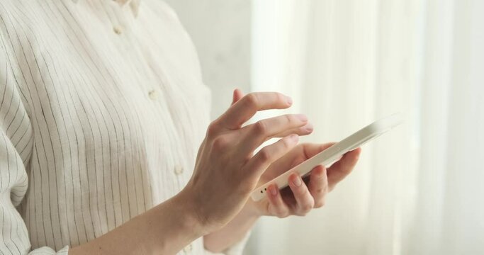 Close-up of a woman hands as she skillfully swipes, scrolls, and browses on her phone. Her fingers glide effortlessly across the screen, revealing her mastery of mobile technology.