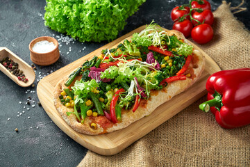 Vegetarian pizza with vegetables and sauce on a board. Dark background