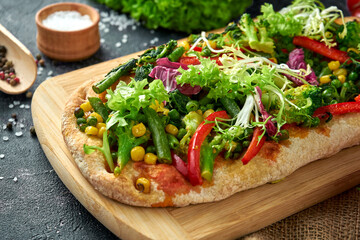 Fototapeta na wymiar Vegetarian pizza with vegetables and sauce on a board. Dark background