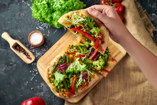 Vegetarian pizza with vegetables and sauce on a board. Dark background
