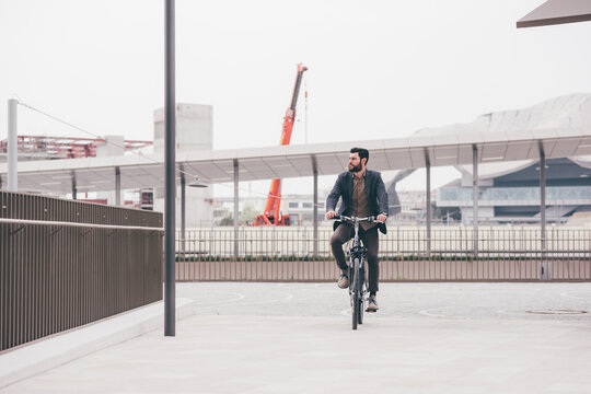 Contemporary bearded young stylish businessman going to work by bike