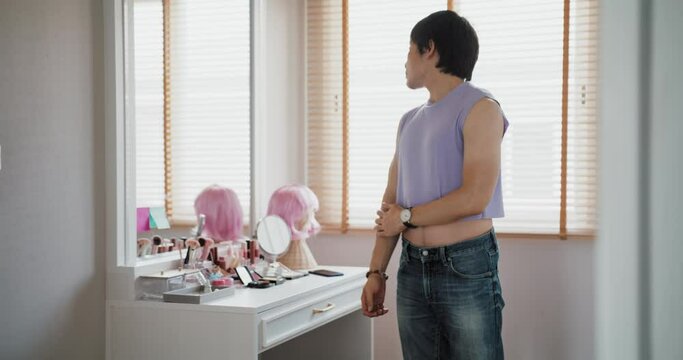 Self-love self-worth as young Gen Z LGBT queer non-binary men looking at perfect body muscle arms in front of mirror at home. Asia people adult guy happy relax enjoy pride month LGBTQIA youth culture.