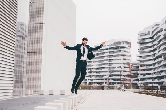 Energetic young bearded professional businessman jumping in mid-air