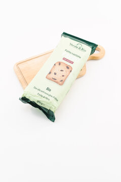 immagine editoriale illustrativa primo piano di confezione di fette biscottate con uvetta, prodotti da filiera biologica, tagliere in legno su superficie bianca
