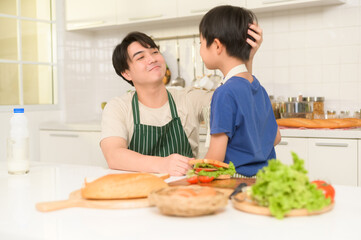 Happy Young Asian father giving support to his son  in kitchen at home