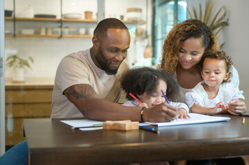 Happy African American parent playing and drawing with daughters in home