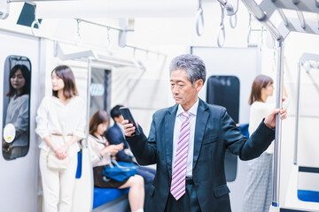 Fototapeta premium 電車内でメールを送るビジネスマン