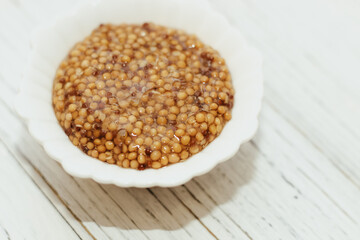 grain mustard in a white bowl on a white table.