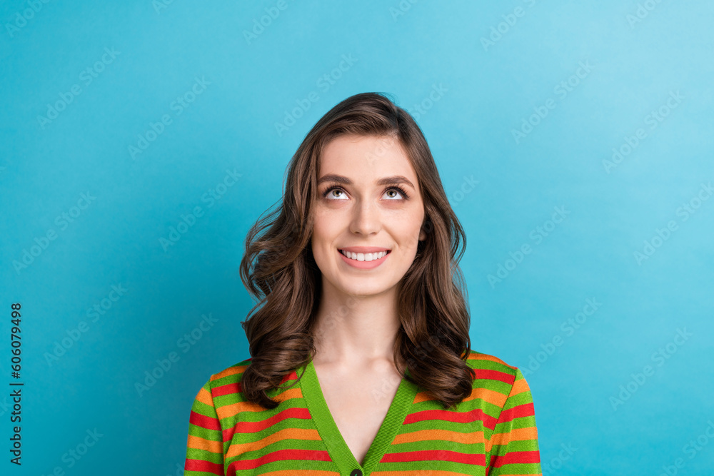 Wall mural Photo of young pretty girl brown curls smiling look empty space up dreaming about future shopping weekend isolated on blue color background