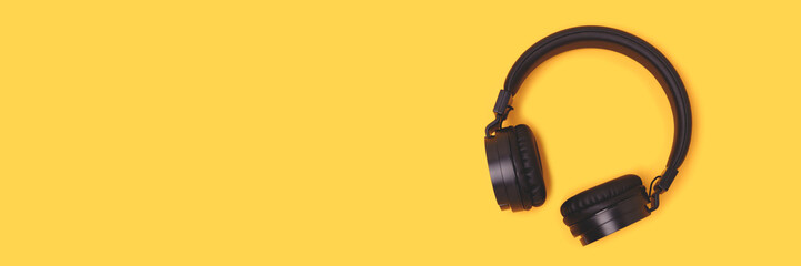 Banner with black wireless headphones on a yellow background. Concept with copy space.