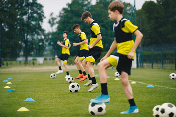 Group of Soccer Players Standing in Line and Kicking Balls at Grass Practice Pitch. Youth...