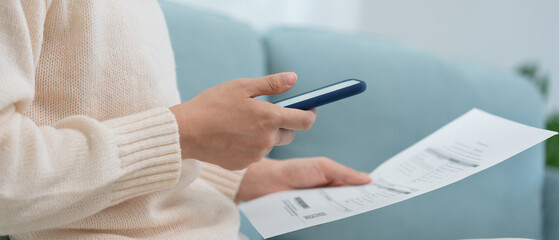 woman use phone scan barcode or QR codes to pay credit card bill after receiving document invoice....