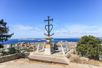 A view of the memorial of lost sealors of the Basilique Notre-Dame-de-la-Garde (la Bonne M&egrave;re) with a majestic view of the city skyline, port, sea and rocky island under a beautiful blue sky 
