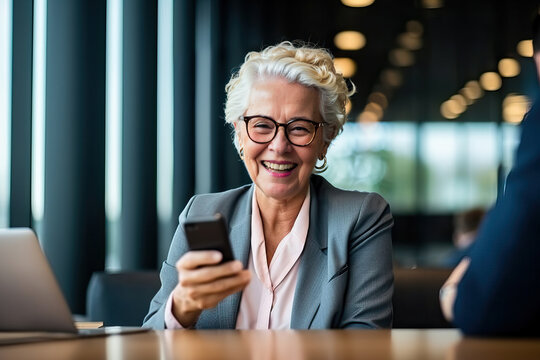 A Senior Business Woman Sitting At A Table Looking At A Cell Phone