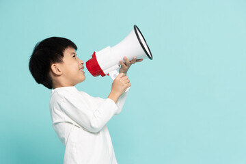 Side of Asian little boy holding megaphone isolated on green background, Speech and announce...