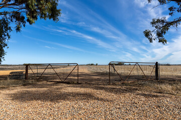 environmental protection, open gate infront of a harvested and dried up field, framed with trees