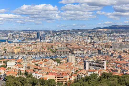 A scenics aerial view of the city of Marseille, bouches-du-rh&ocirc;ne, France with the old port (vieux port) in the background under a majestic blue sky and some white clouds