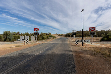 travel australia, street sign "railway crossingt" written in English, where a road and a railroad crossing each other 