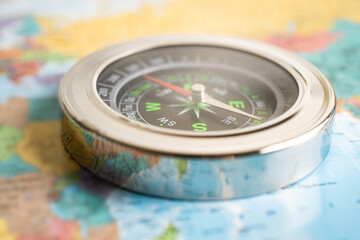 Compass on blur world map background to travel, geography, tourism and exploration concept.