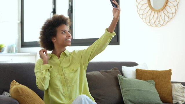 Selfie web camera view joyful young African American curly beautiful woman holding keys in hands, posing for photo, recording streaming video stories online, sharing own apartment purchase experience.
