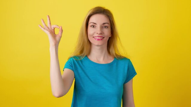 Woman, ok hand, wink and smile excited emotion, sign or symbol feeling happy. Lady with emoji okay Yes gesture, mock up for success, approval, motivation or review, opinion in studio yellow background