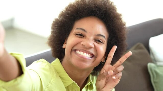 Selfie web camera view joyful young African American curly beautiful woman holding keys in hands, posing for photo, recording streaming video stories online, sharing own apartment purchase experience.