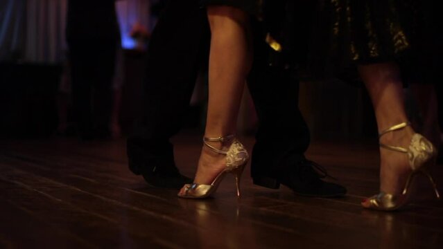 foot steps in the floor of a milonga dancing party, peopler dancing Argentine Tango in a moody bar cafe