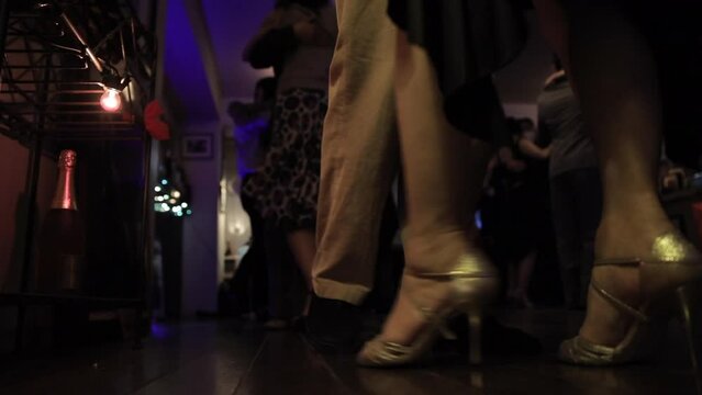 foot steps in the floor of a milonga dancing party, peopler dancing Argentine Tango in a moody bar cafe