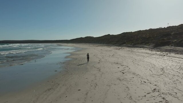 Girl walking on a sandy beach by the ocean