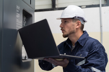 Male engineer worker working with laptop computer for control machine in the workshop. Male worker working with lathe machine with safety uniform and helmet in the industry factory