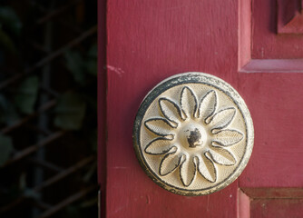 antique white metal doorknob detail on a red wooden door. worn. vintage house design. exterior building in Obidos, Portugal.